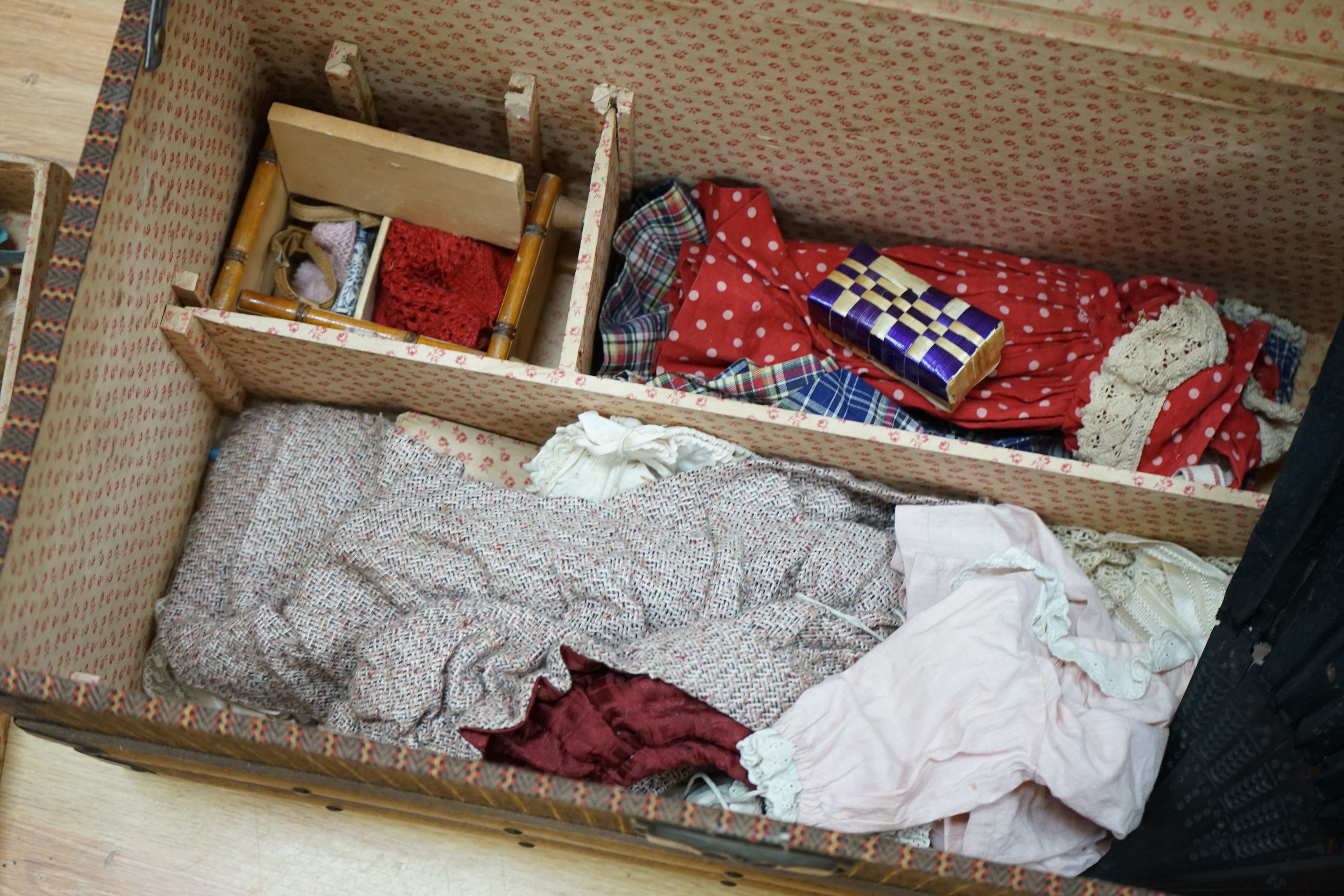 A Tête Jumeau bisque doll, closed mouth and paperweight eyes, jointed wood and composition body, two other French bisque dolls and assorted clothing, all contained within a three-layer wood and metal-bound cabin trunk, J